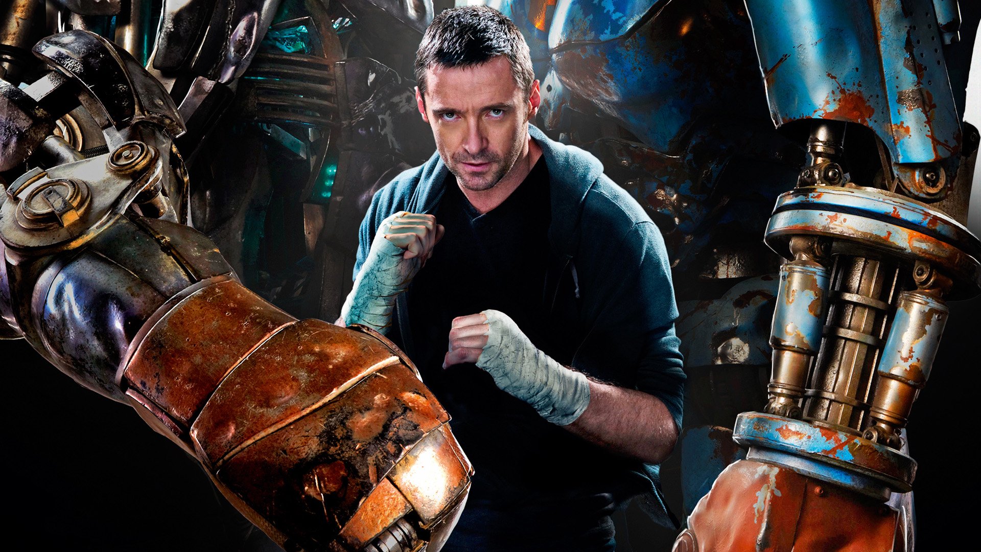 HD desktop wallpaper featuring Hugh Jackman in his role from the movie Real Steel, positioned between two large futuristic robots in an intense stance.