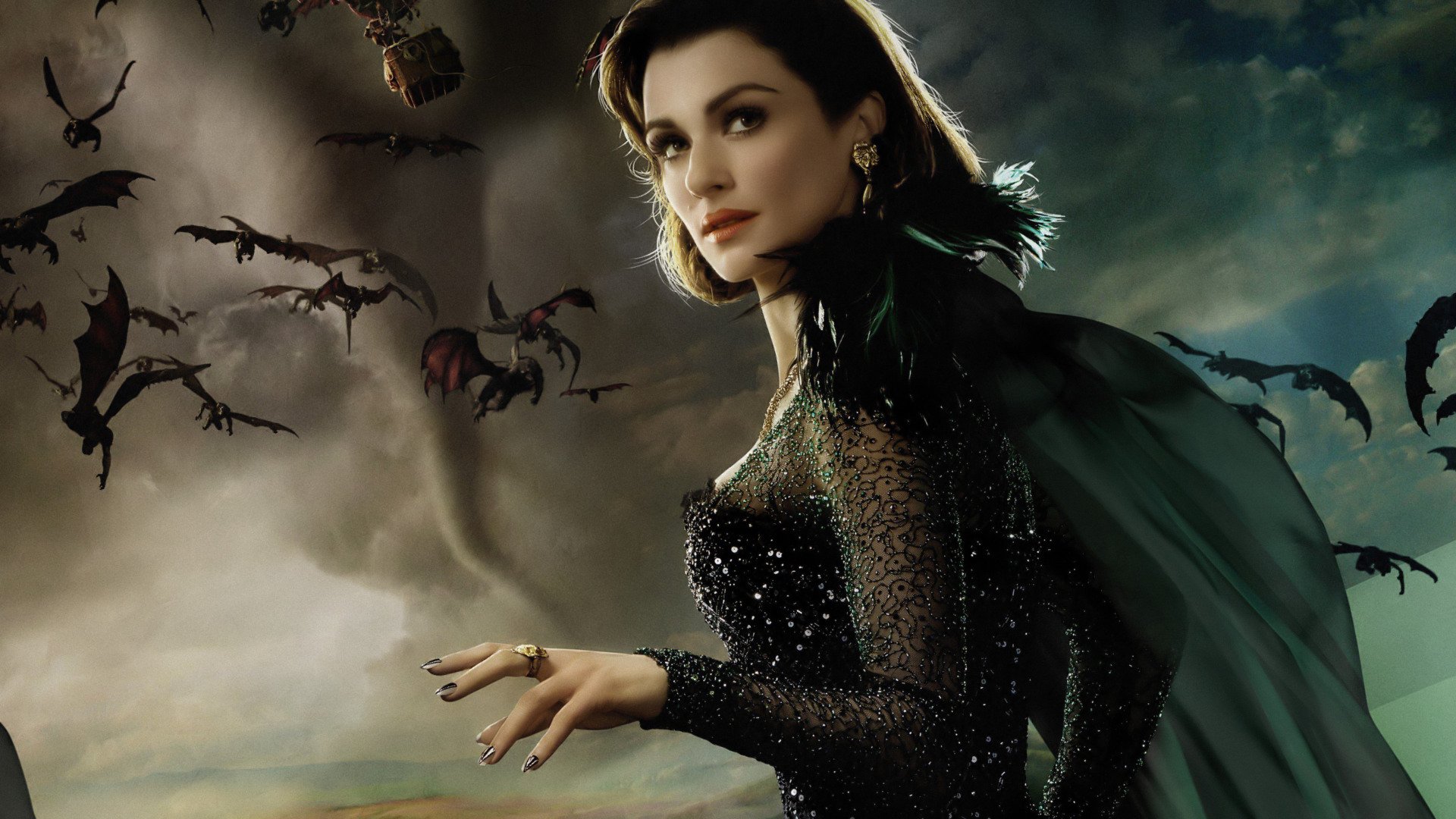 HD PC desktop wallpaper: actress from the movie Oz the Great and Powerful in a dark glittering gown and cape, bats swirling against a storm-tossed sky.