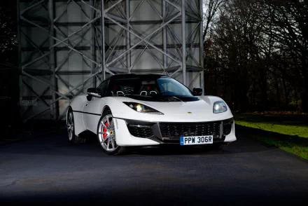 White Lotus Evora supercar parked outdoors, showcased in sharp 4K Ultra HD detail against a geometric metal backdrop and natural surroundings.