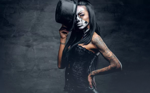 HD desktop wallpaper featuring a brunette model with a sugar skull face paint and tattoos, wearing a corset and holding a hat against a dark background.