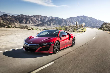 A red Acura NSX supercar drives through a scenic mountain road under a clear blue sky. This HD desktop wallpaper captures the sleek design and powerful presence of the vehicle.