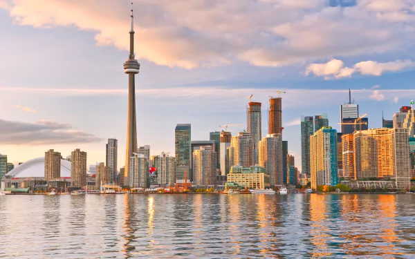 Toronto cityscape featuring towering skyscrapers and the iconic CN Tower at sunset, reflected in the waters. This HD wallpaper captures the vibrant atmosphere of this Canadian metropolis.