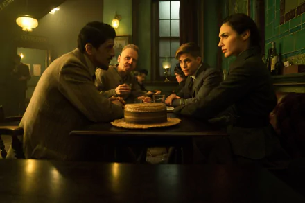 HD desktop wallpaper featuring Gal Gadot and Chris Pine in a scene from the movie Wonder Woman, with the characters seated around a table in a warmly lit room.