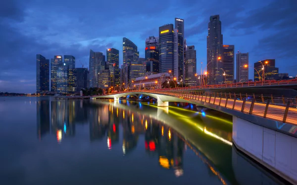 Night view of Singapore's Esplanade Bridge and illuminated skyscrapers reflecting on the calm water, captured in a high-definition cityscape wallpaper.