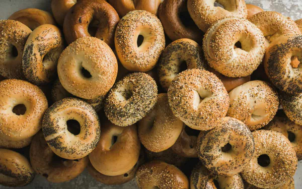 HD PC desktop wallpaper background: close-up pile of bagels (bread, food) with golden crusts and a mix of sesame and poppy seeds.