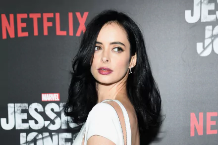 HD desktop wallpaper of a dark-haired woman in a white dress looking over her shoulder against a red-and-black premiere backdrop with Netflix and Jessica Jones logos.