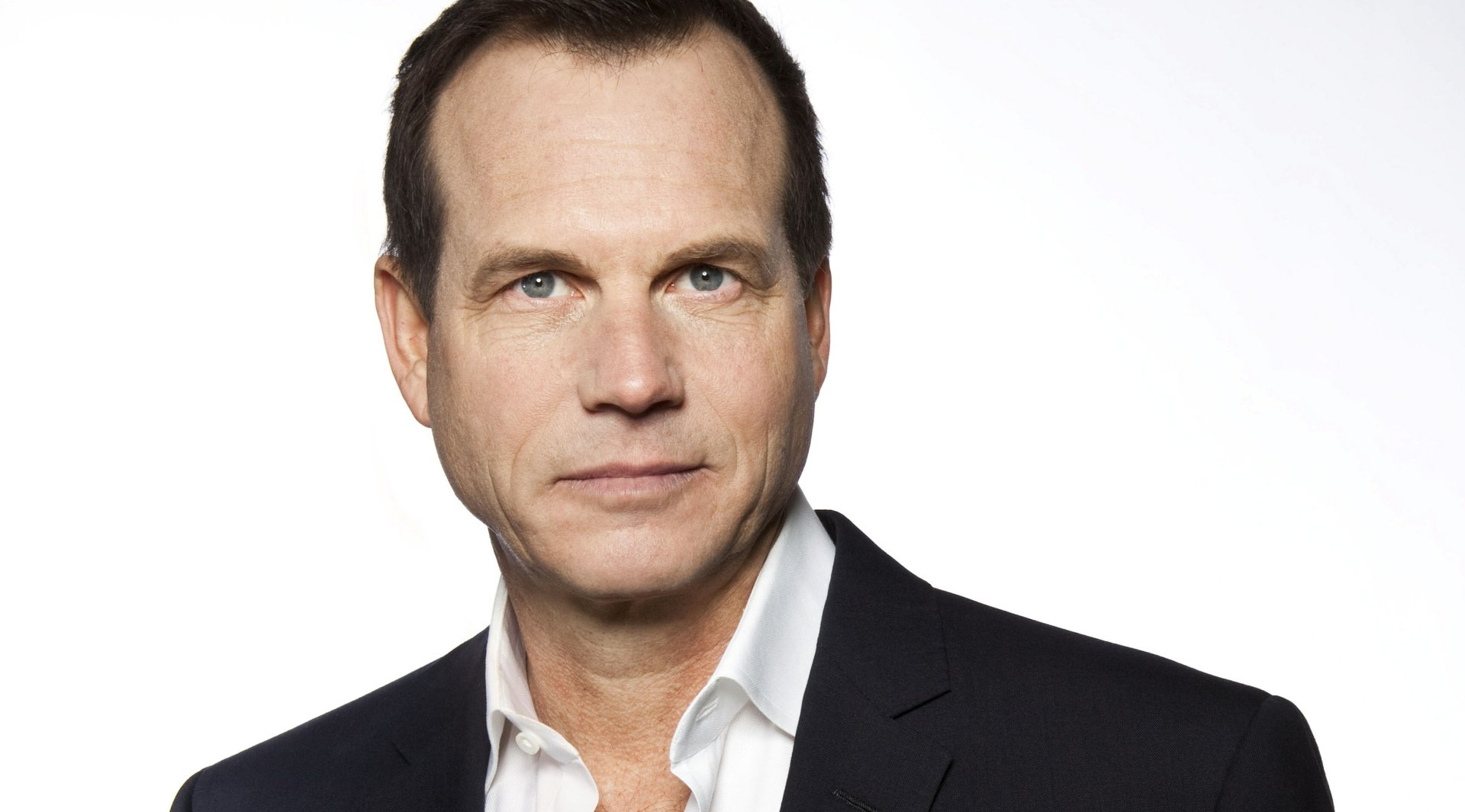 A high-definition wallpaper featuring Bill Paxton, showcasing his confident expression and sharp attire against a light background.