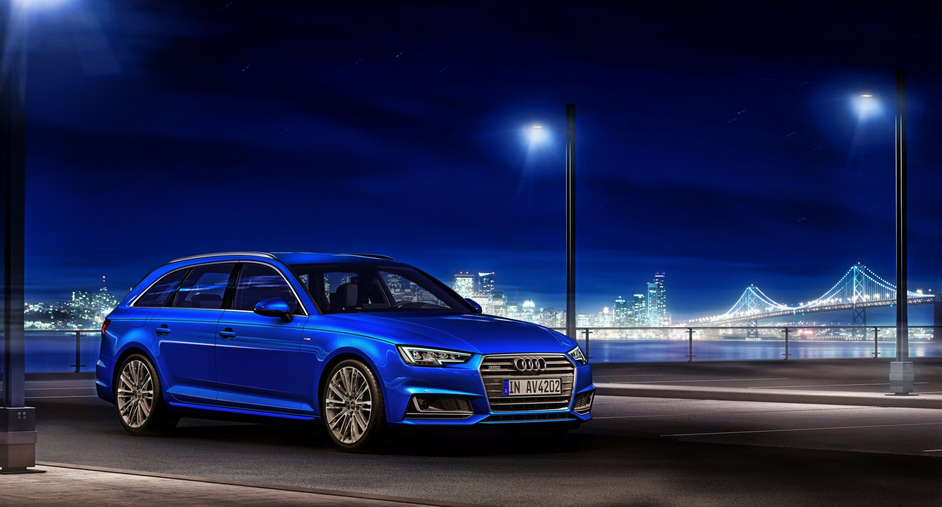 A blue Audi A4 car parked on a city street at night with a bridge and illuminated skyline in the background, shown in 4K Ultra HD.