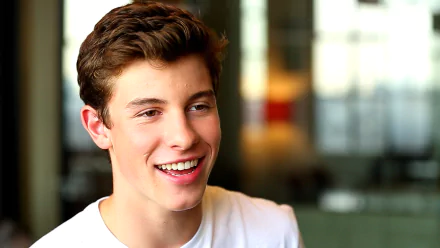 HD desktop wallpaper featuring a smiling person in a white shirt with a blurred background, tagged as Shawn Mendes.