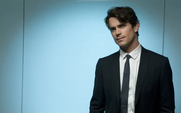 HD desktop wallpaper featuring a man in a black suit and tie with a light blue background.