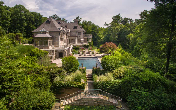 2K Quad HD PC desktop wallpaper/background of a luxurious man-made mansion and pool framed by terraces and lush gardens.