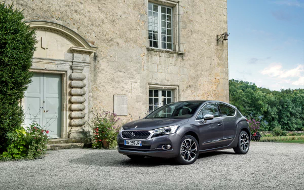 Silver Citroën DS4 compact car parked in front of a historic stone building with greenery in the background, captured in 4K Ultra HD quality.