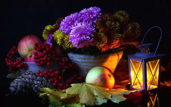 Still life HD wallpaper featuring a glowing lantern, bowl of chrysanthemums, apples, pine cones, berries, and autumn leaves in warm, low light photography.