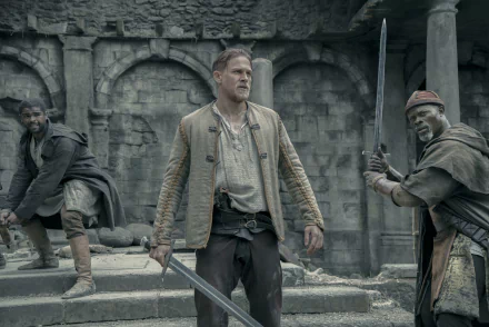 HD desktop wallpaper featuring Djimon Hounsou and Charlie Hunnam in King Arthur: Legend of the Sword, showcasing a dramatic scene of the movie set in an ancient, stone-walled environment.