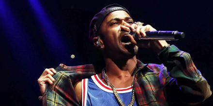 Big Sean performing passionately on stage, wearing a colorful outfit, captured in a dynamic moment. A vibrant HD desktop wallpaper celebrating music and artistry.