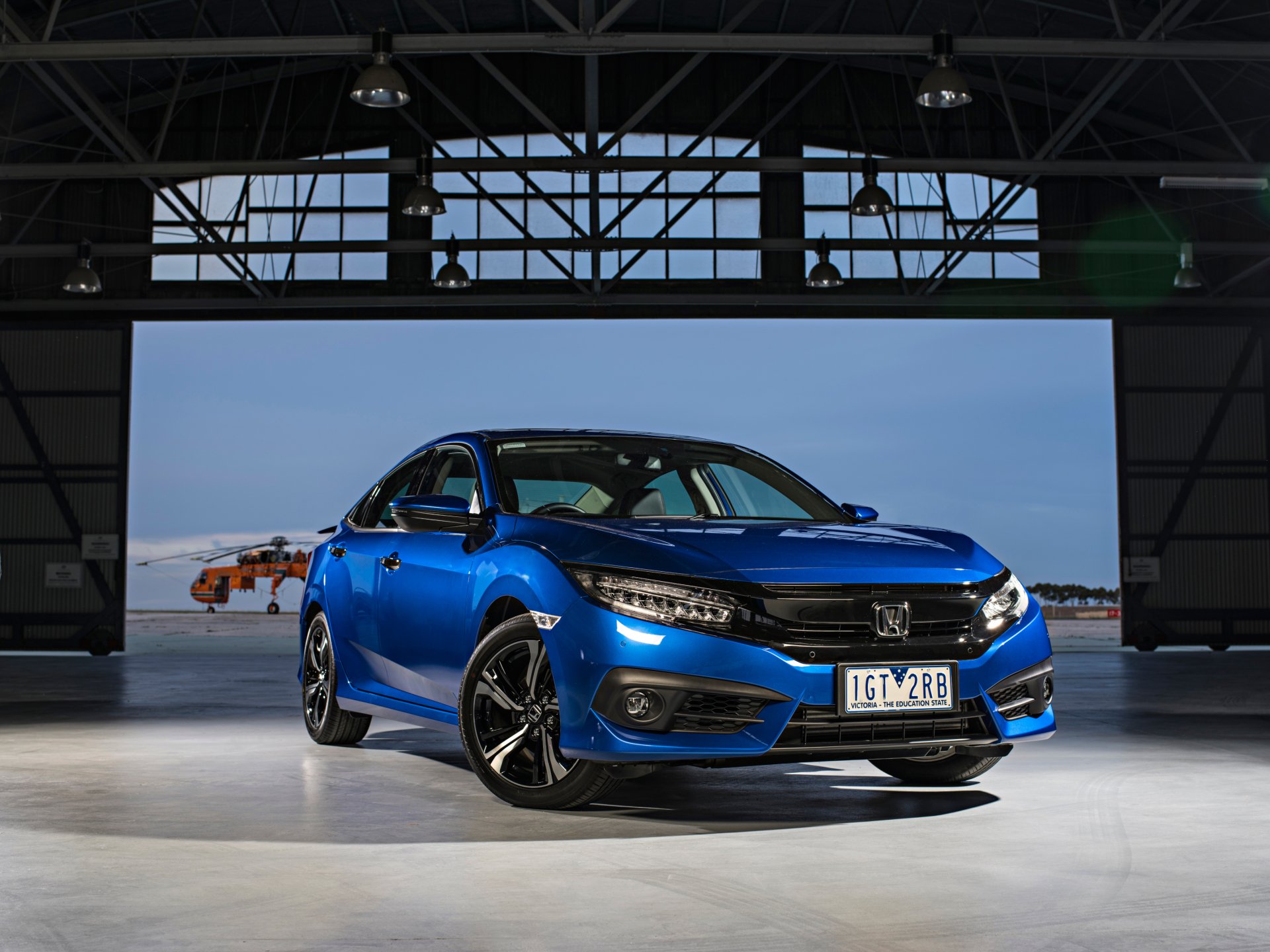 Blue Honda Civic parked inside a spacious industrial garage, featured as an HD PC desktop wallpaper and background.