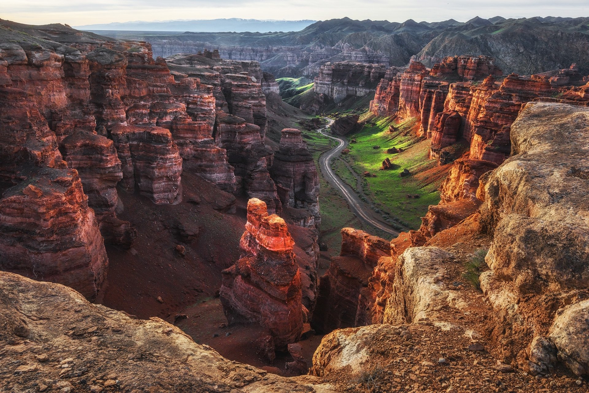 HD desktop wallpaper of a stunning canyon landscape with rugged cliffs and green patches. The winding path through the canyon highlights the natural beauty.
