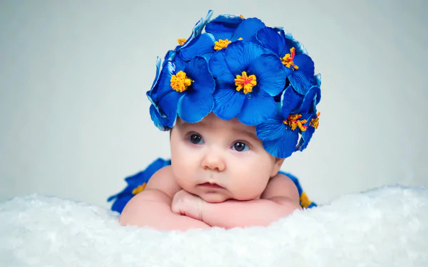 Adorable baby wearing a wreath of vibrant blue flowers, captured in a 4K Ultra HD photo with a soft, light background.