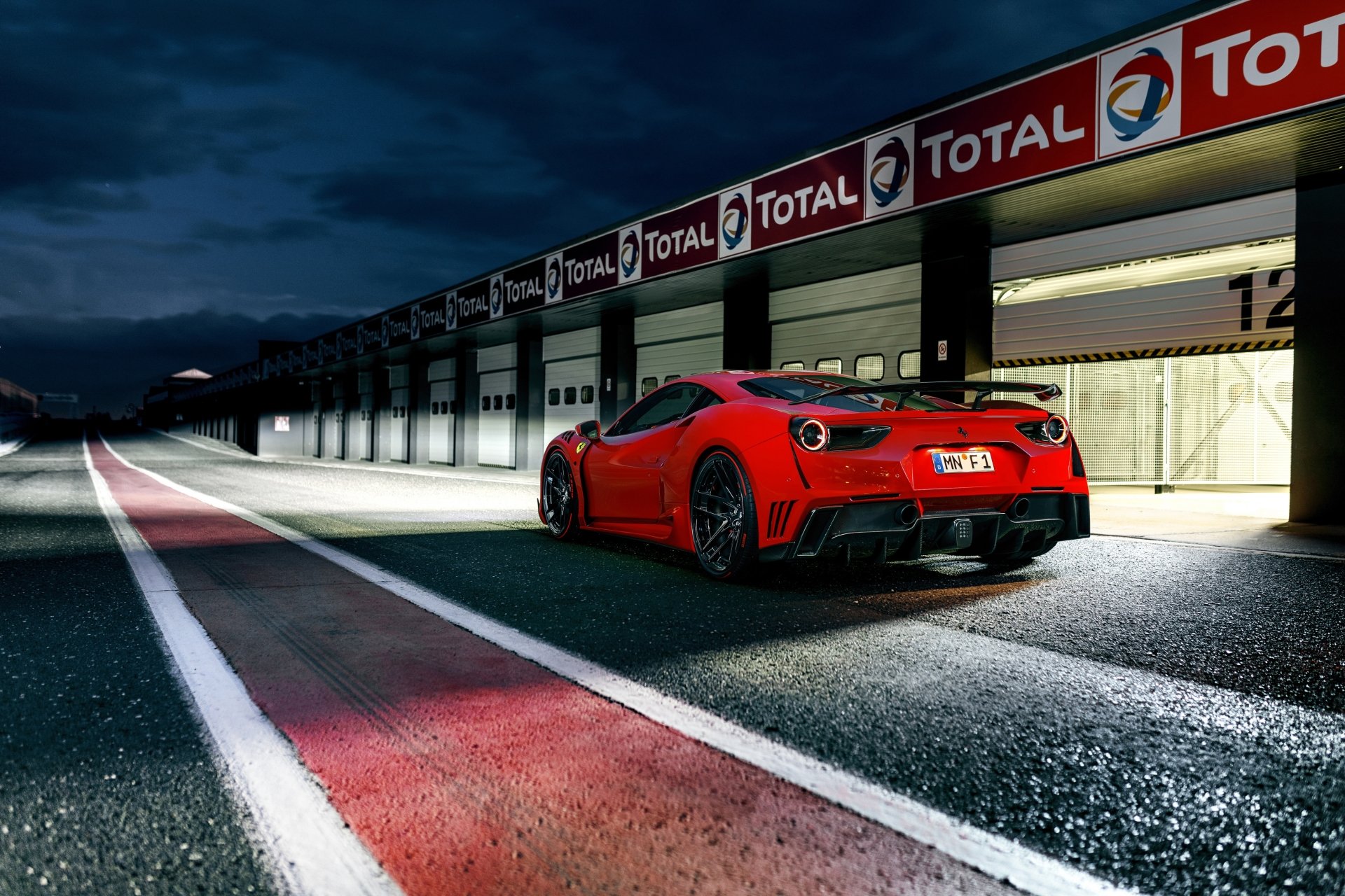 Red Ferrari 488 GTB supercar parked by a racing pit lane at night, captured in 4K Ultra HD for a stunning PC desktop wallpaper background.