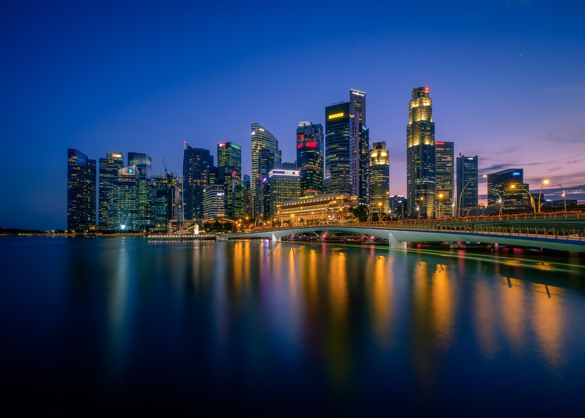 HD PC desktop wallpaper: Esplanade Bridge and Singapore skyline at night, illuminated skyscrapers and city buildings reflected on calm water, a striking man-made urban backdrop.