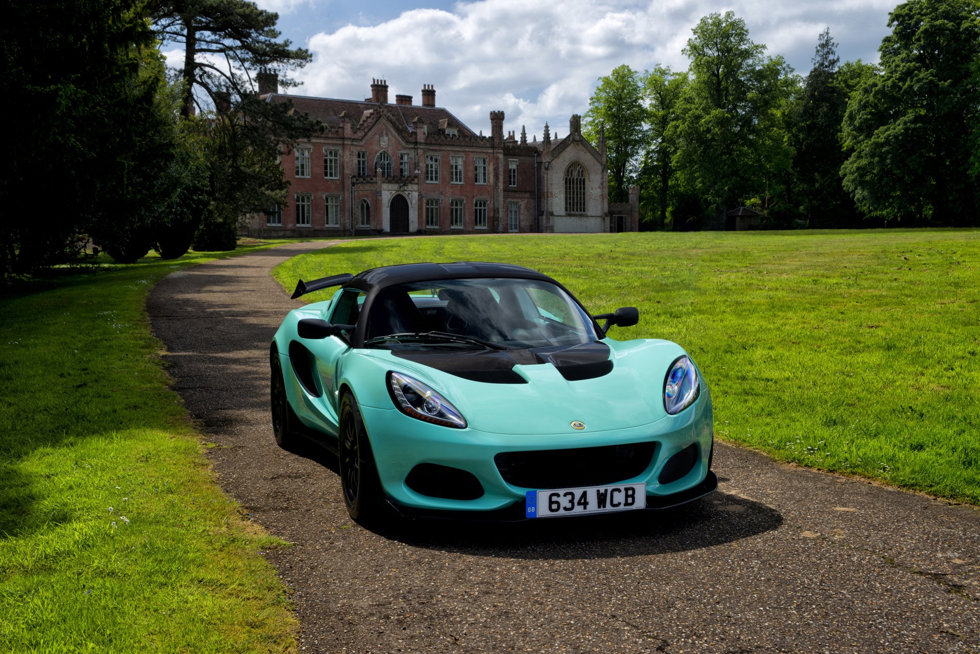 A mint green Lotus Elise supercar parked on a driveway in front of a historic mansion, captured in 4K Ultra HD as a PC desktop wallpaper and background.