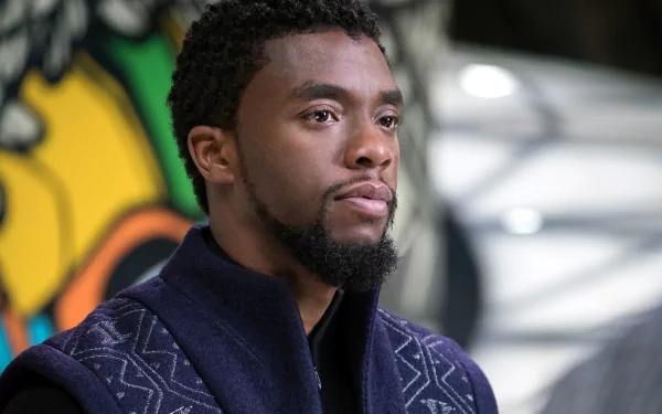 HD desktop wallpaper featuring Chadwick Boseman as Black Panther. He is wearing a dark, patterned garment with a colorful background.