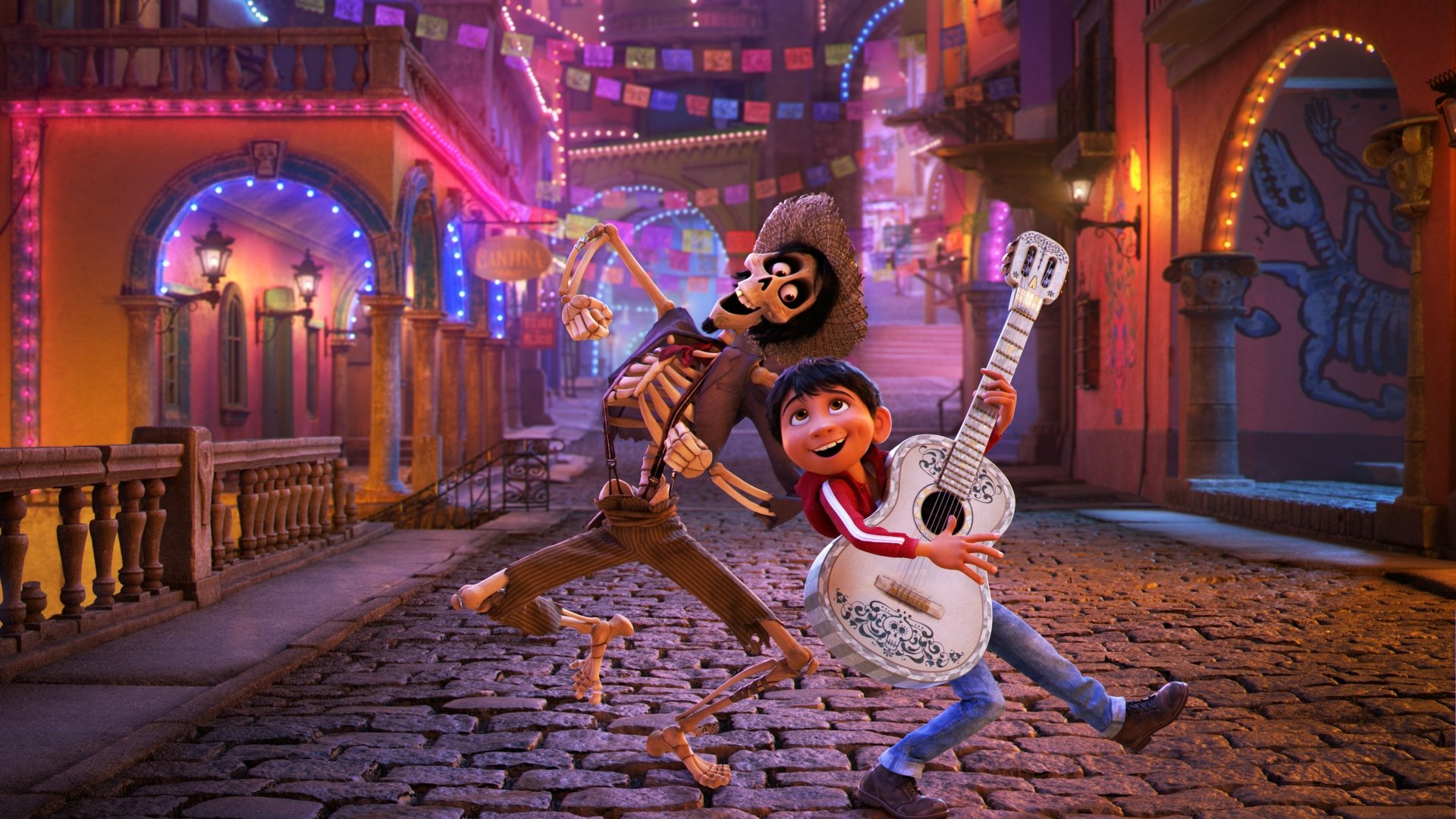 HD desktop wallpaper featuring Miguel Rivera and Hector from the movie Coco, set in a vibrant, colorful street scene at night.