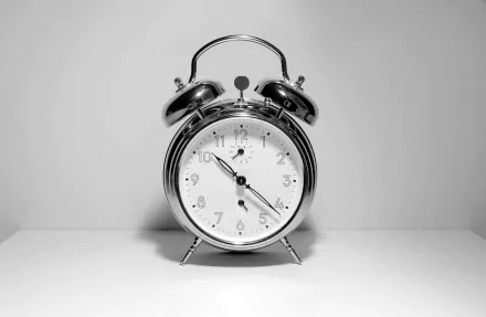 HD desktop wallpaper featuring a classic twin-bell alarm clock in monochrome, centered on a simple background.