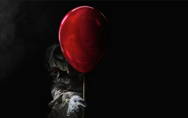 HD wallpaper featuring Pennywise the clown from the movie It (2017). He is partially obscured by a red balloon, creating a foreboding and eerie atmosphere. The background is dark and ominous.