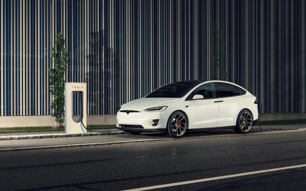 White Tesla Model X electric car charging at a station against a striped industrial wall — 4K Ultra HD PC desktop wallpaper background showcasing Tesla Motors vehicle.