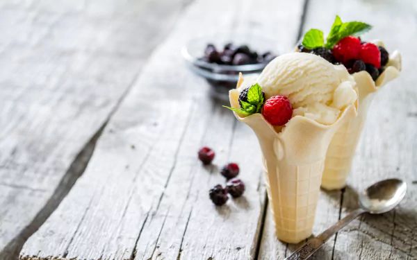 4K Ultra HD still life of creamy ice cream scoops served in waffle cones, garnished with fresh berries and mint leaves on a rustic wooden surface.