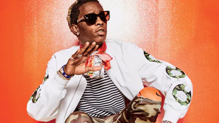 A vibrant HD wallpaper featuring Young Thug, styled in a striped shirt and camo pants, with a colorful background that emphasizes his unique fashion and artistic presence.