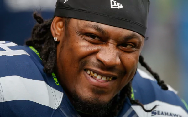 HD desktop wallpaper of Marshawn Lynch in his Seattle Seahawks gear, smiling at the camera.