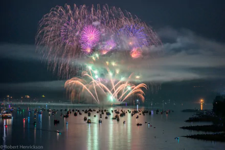 HD desktop wallpaper showcasing a colorful fireworks display over the sea at night in Vancouver, with boats scattered across the water.