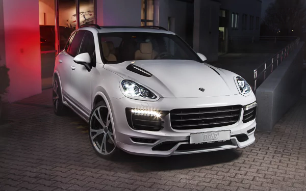 White Porsche Cayenne SUV parked on a dimly lit street, showcasing its sleek design and modern headlights in an HD desktop wallpaper background.