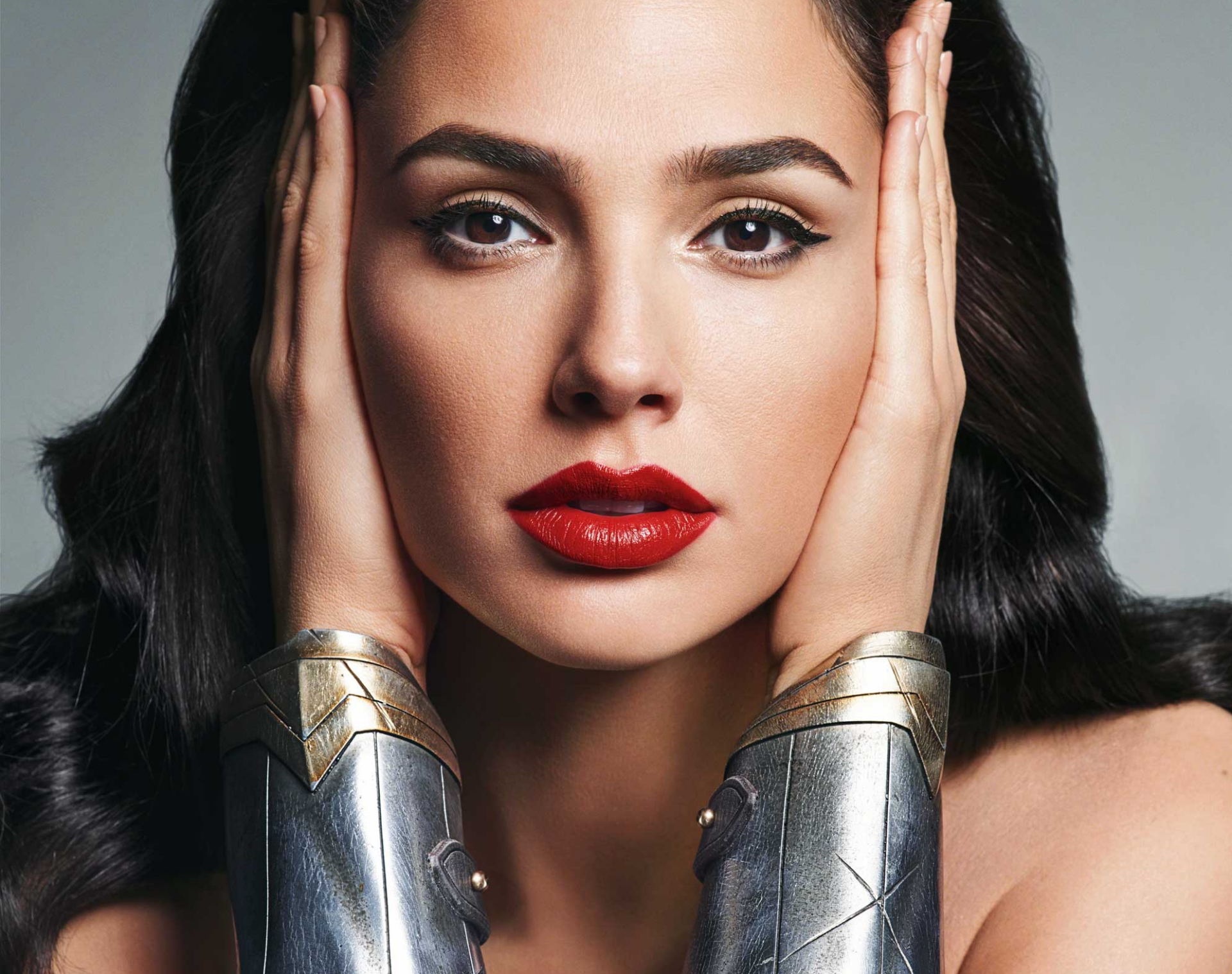 Close-up HD wallpaper of Gal Gadot as Wonder Woman, highlighting her brown eyes, red lipstick, and iconic silver wrist cuffs.