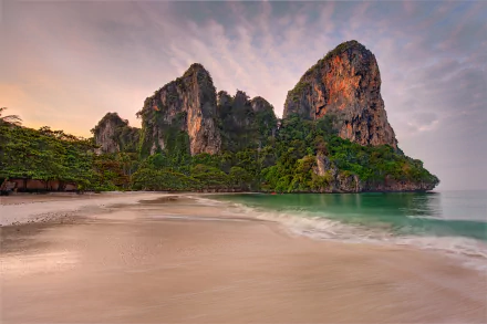 4K Ultra HD PC wallpaper of a tropical Thailand beach: soft sand, emerald water and dramatic limestone cliffs beneath a pastel dawn sky.