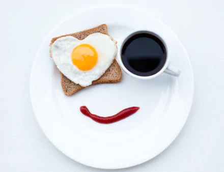 HD desktop wallpaper showing a breakfast plate with a heart-shaped fried egg on toast, a cup of coffee, and a ketchup smiley face. Tags: bread, cup, coffee, face, egg, food, breakfast.