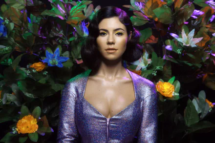 2K Quad HD PC wallpaper, music-themed: stylized female singer in a shimmering purple outfit amid lush foliage with yellow and blue flowers.