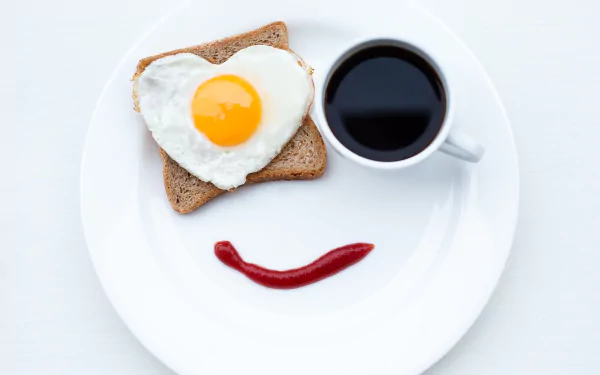 HD desktop wallpaper showing a breakfast plate with a heart-shaped fried egg on toast, a cup of coffee, and a ketchup smiley face. Tags: bread, cup, coffee, face, egg, food, breakfast.