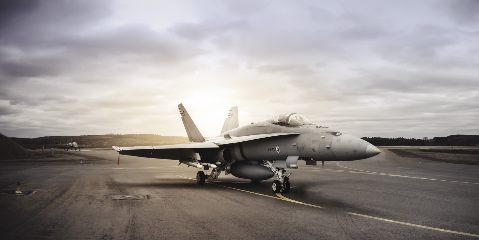 A McDonnell Douglas F/A-18 Hornet jet fighter warplane on a runway under a cloudy sky in this high-definition military aircraft desktop wallpaper.