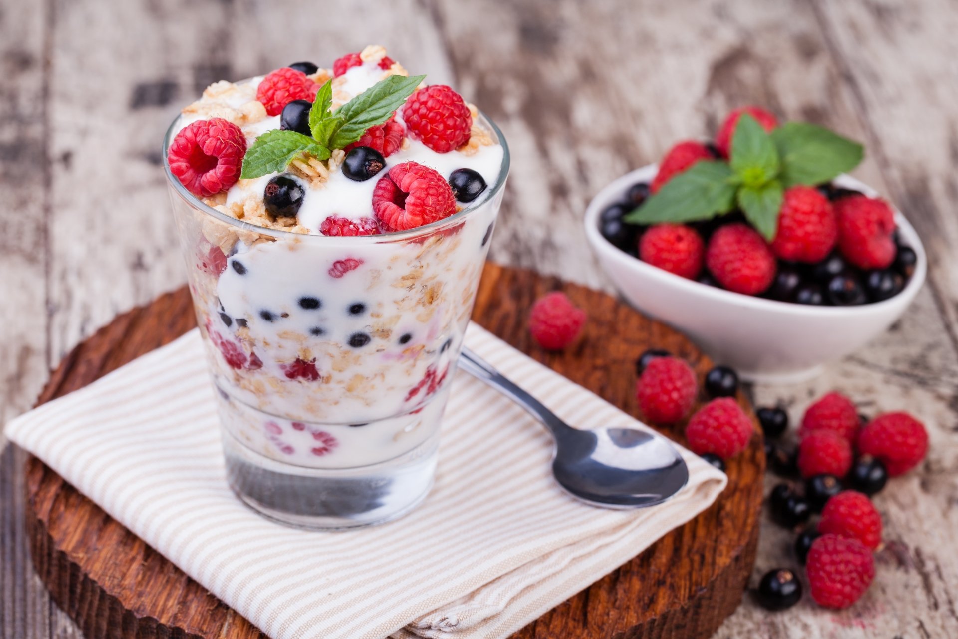 A vibrant 4K Ultra HD desktop wallpaper featuring a glass of yogurt layered with blueberries, raspberries, and fresh berries, garnished with mint on a rustic wooden surface.