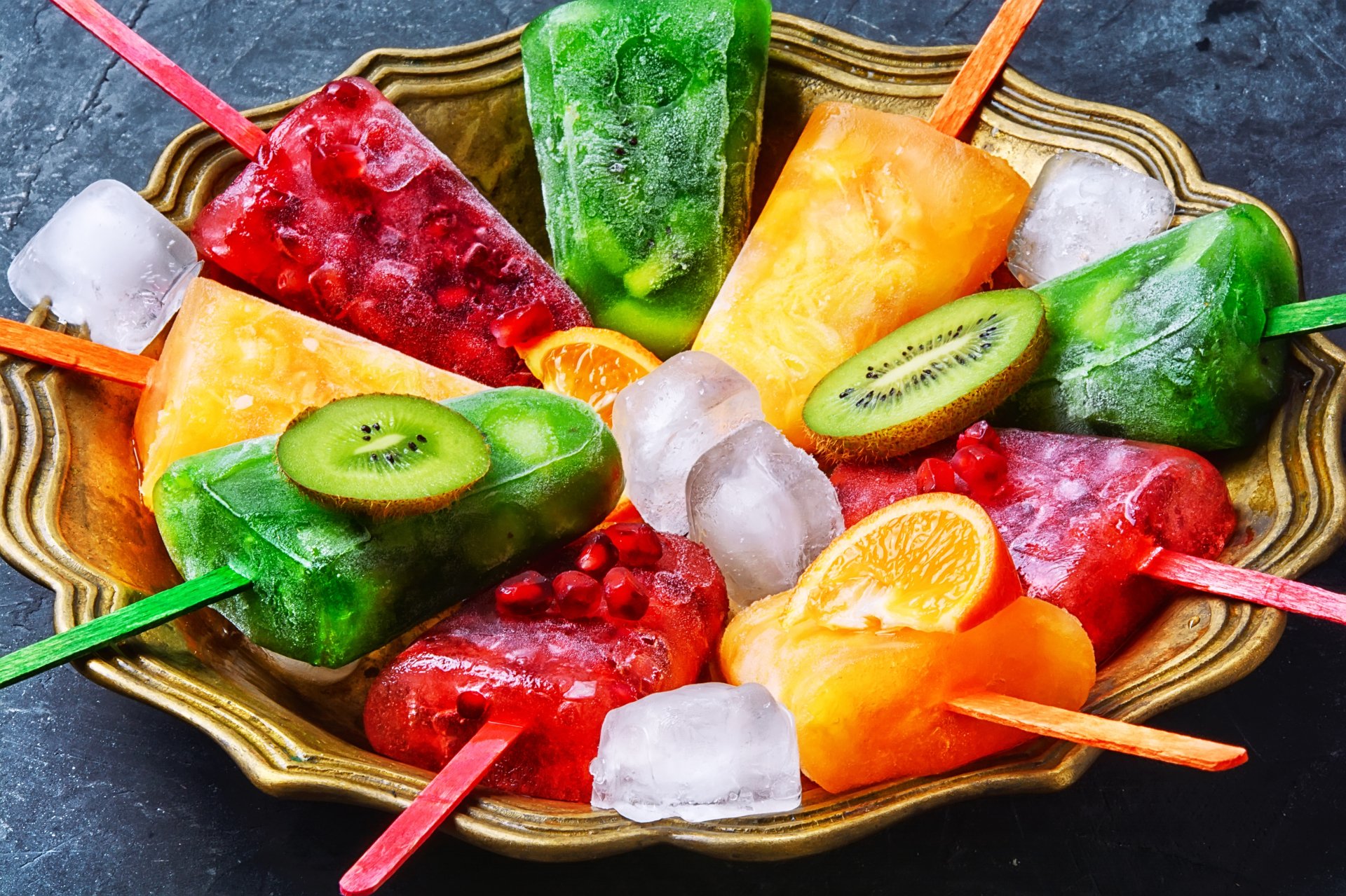 Colorful ice cream popsicles with slices of fruits arranged in a bowl with ice cubes. HD desktop wallpaper and background featuring vibrant sweets and food.