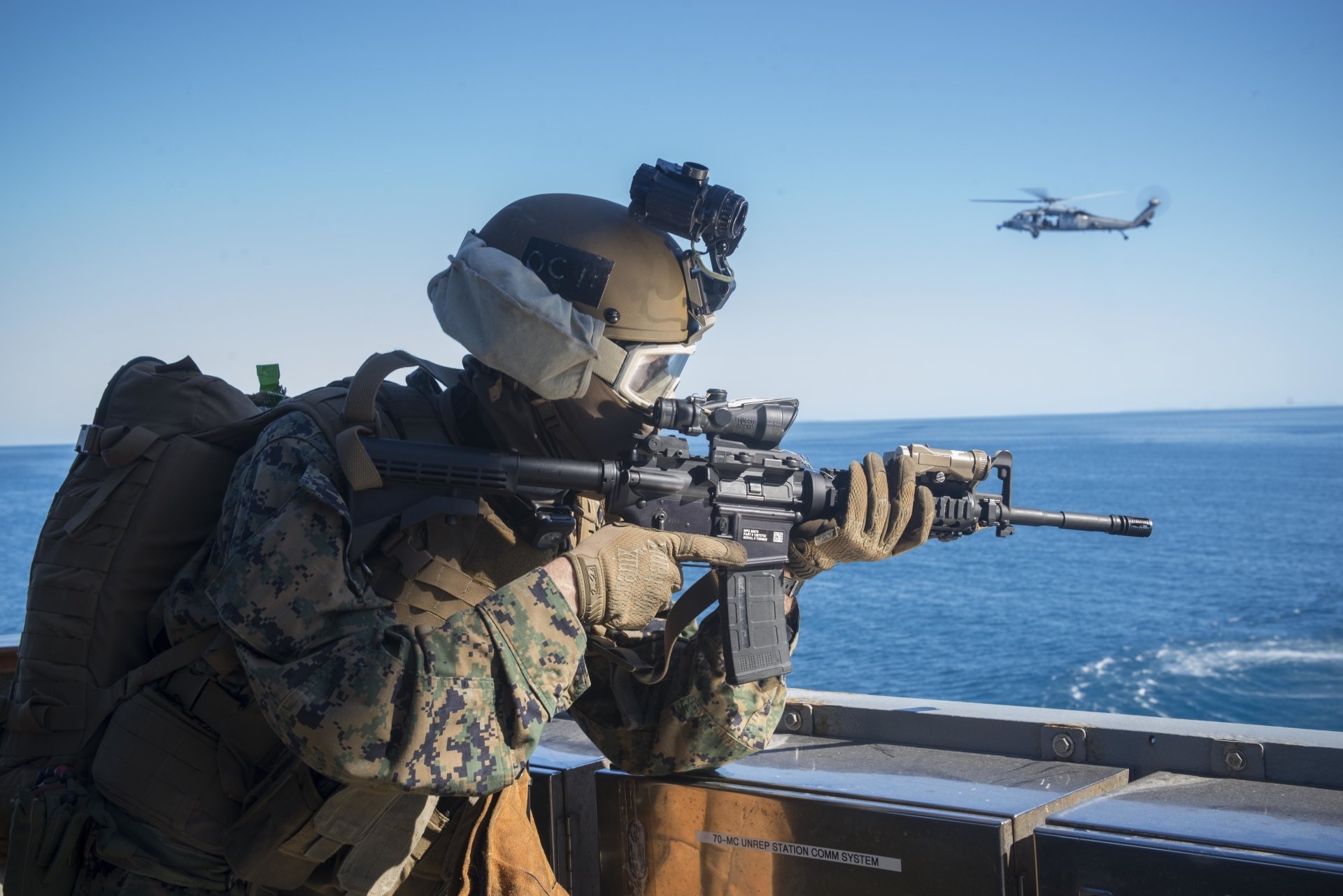 Marine soldier aiming an M4 Carbine rifle aboard a ship, with the ocean and a helicopter in the background, captured in 4K Ultra HD detail.