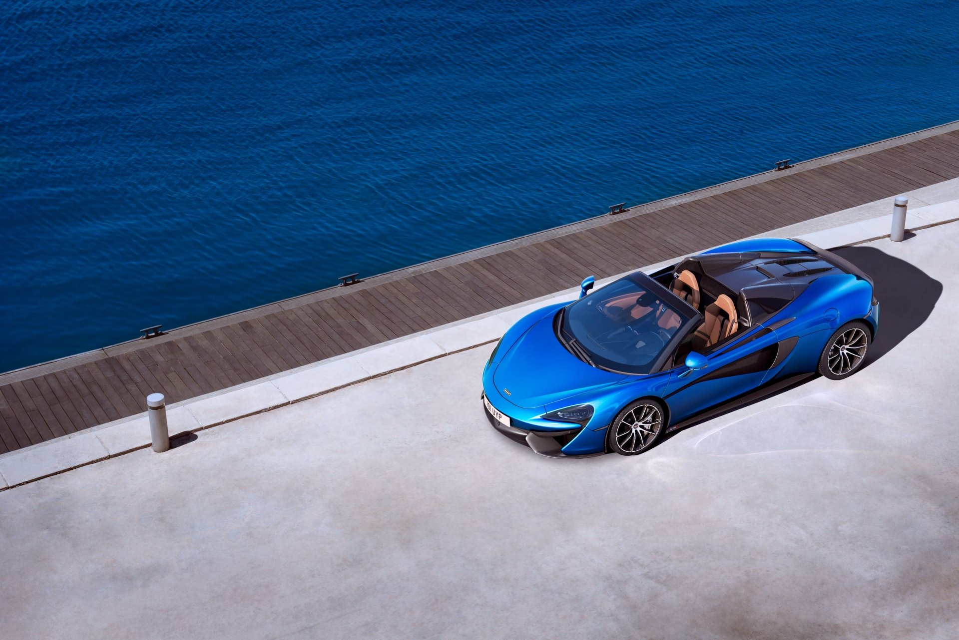 A blue McLaren 570S supercar parked by a waterfront, captured in 4K Ultra HD for a PC desktop wallpaper and background.