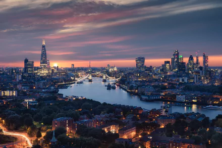 HD desktop wallpaper featuring a breathtaking London cityscape at sunset, showcasing the Thames River, Tower Bridge, and prominent skyscrapers glittering against the evening sky.