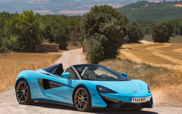 Bright blue McLaren 570S supercar parked on a rural road, surrounded by golden fields and trees, captured in 4K Ultra HD for a stunning PC desktop wallpaper.