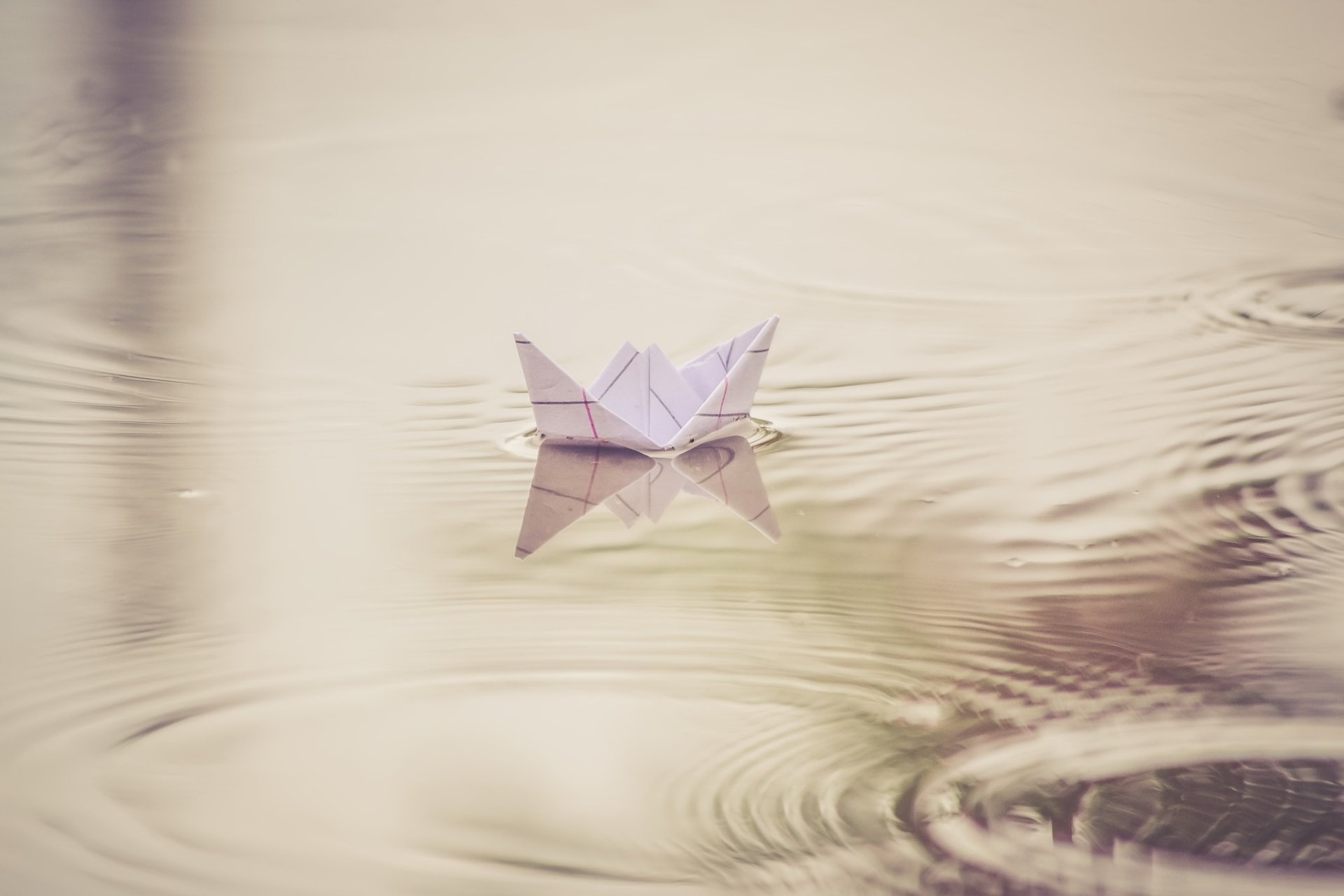 HD PC desktop wallpaper: an origami paper boat floating on calm water with gentle ripples around the man-made craft.