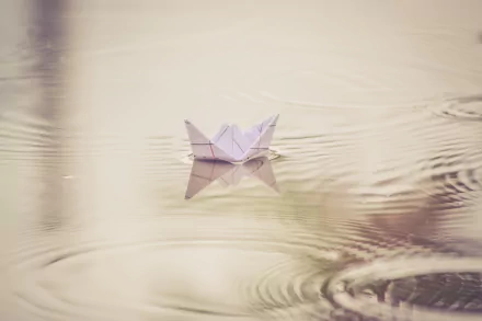 HD PC desktop wallpaper: an origami paper boat floating on calm water with gentle ripples around the man-made craft.