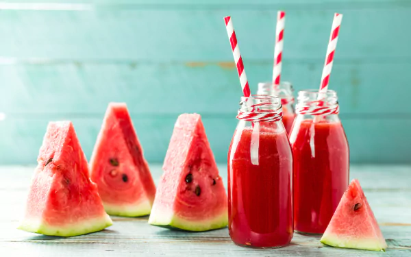 4K Ultra HD wallpaper showing fresh watermelon slices and vibrant red watermelon smoothie drinks in glass bottles with red-and-white striped straws.